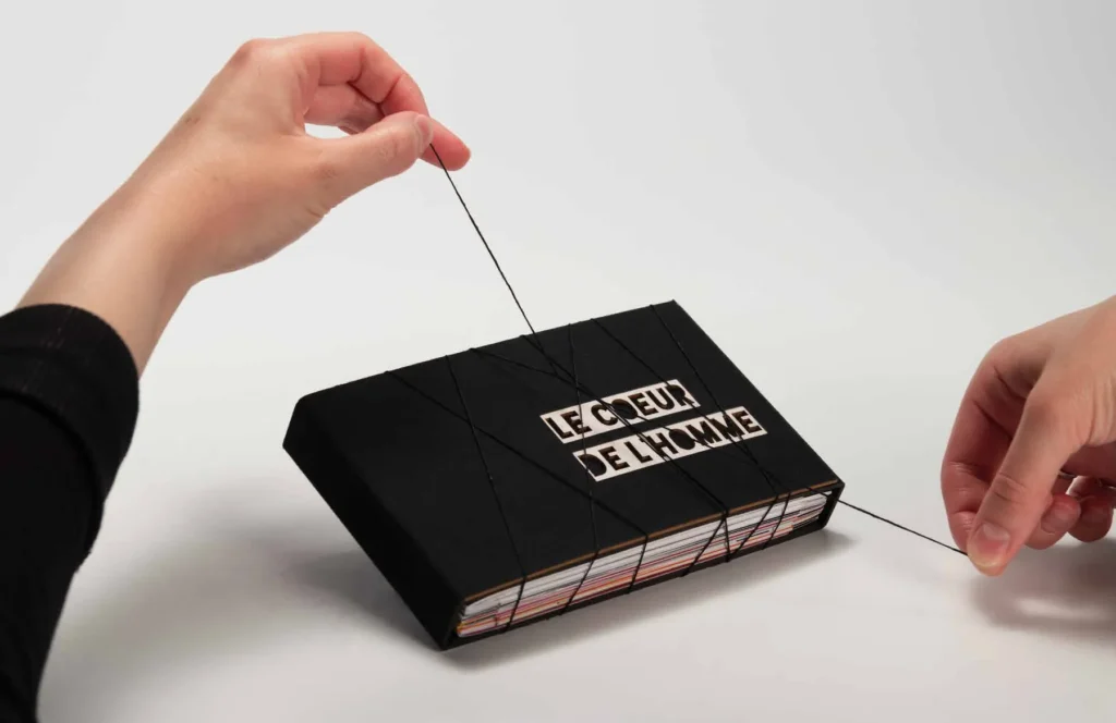 Livre noir « Le cœur de l’homme » sur une table, pendant la couture de la reliure copte.
