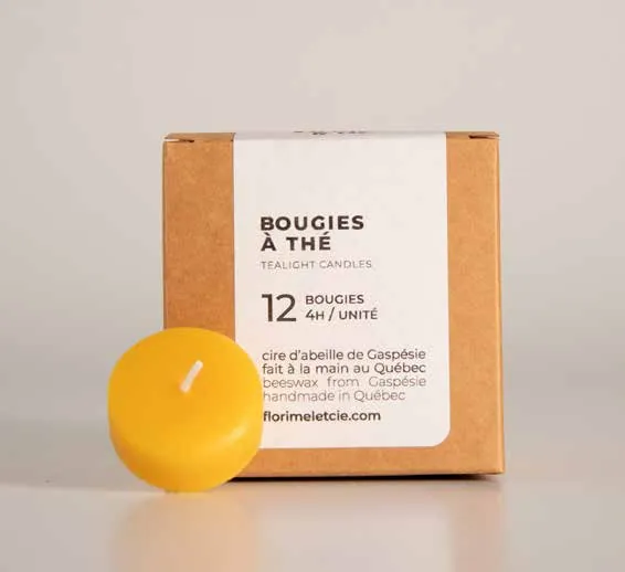 Boîte de 12 bougies à thé en cire d’abeille Florimel & Cie, avec une bougie allumée à côté.