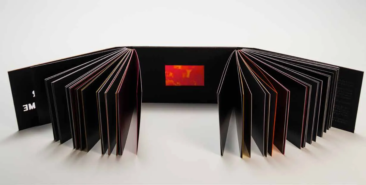 Livre déplié en accordéon, tranches rouges et pages noires.